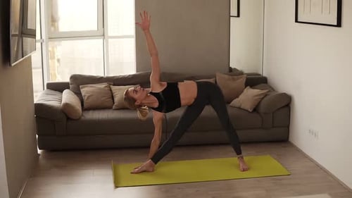 Slender Girl in Black Sports Clothing is Exercising Yoga at Home During Individucal Practice Working