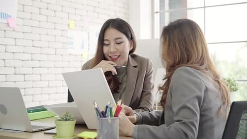 Two young Asian businesswomen working together in office