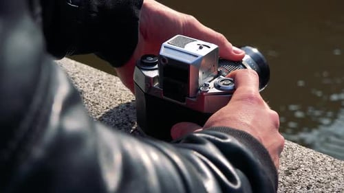 A Man Uses Zoom on a Camera on the Edge of a Stone Bridge - Closeup