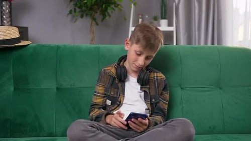 Teen Relaxing on Couch Using Smartphone