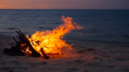 Loderndes Lagerfeuer am Strand, Sommerabend. Lagerfeuer in der Natur als Hintergrund. Brennendes Holz