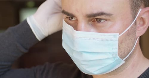 Adult Adjusting a Surgical Mask with Gloves