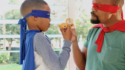 Father and Son in Superhero Costumes Eating Cupcakes