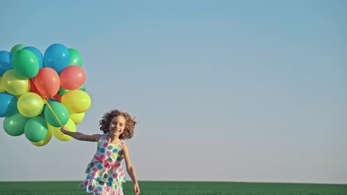 Happy Girl with Colorful Balloons in Field