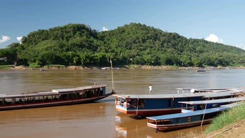 Long-tail boat arriving at the shore of the Mekong river in Luang Prabang