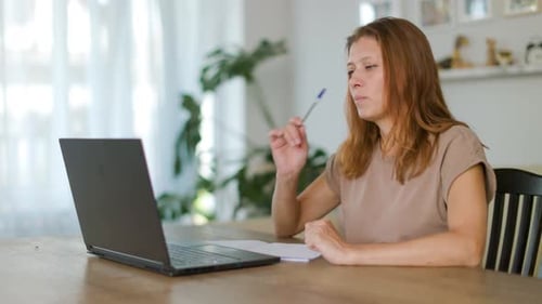 Woman At Table Participates in Video Call