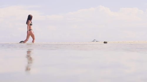 Young Woman in Bikini Walking on Sea Water at Sandy Beach on Paradise Resort. Low Angle View