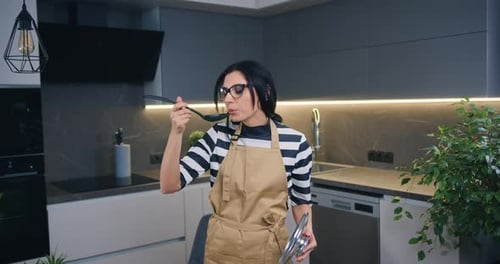 Woman Tasting Food in Modern Kitchen