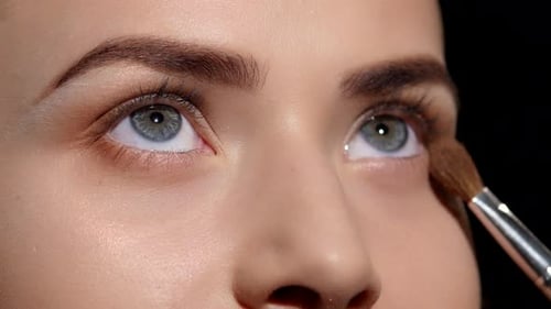 Makeup Artist Applying Eyeshadow on Eyelid. Black. Closeup