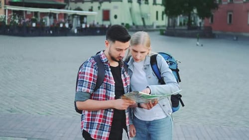 Mann und Frau halten Karte in der Hand und suchen einen Platz auf dem Stadtplatz