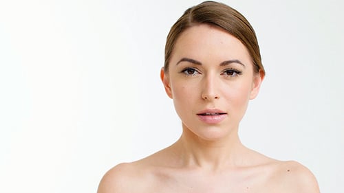 Woman with Makeup Touching Face and Smiling