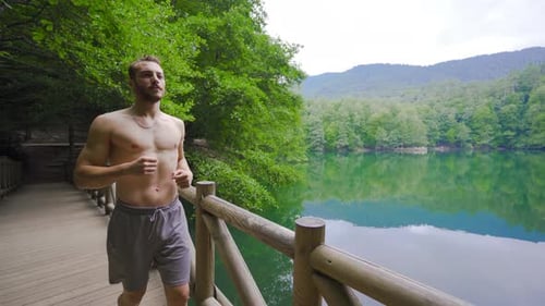 Muscular male running in the forest.