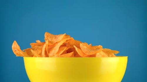 Potato Chips Fill Yellow Bowl on Blue Background