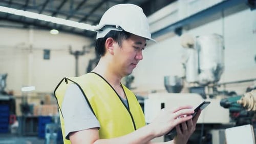 Young Asian Male Factory Worker Using a Digital Tablet