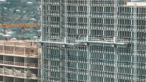 Arbeiter arbeiten während des Baus eines Hochhauses in einer Bauwiege auf Gerüsten