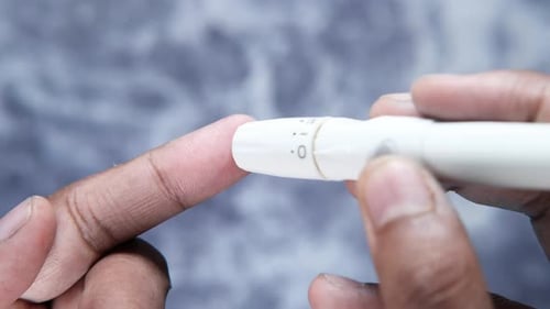 Hand eines jungen Mannes misst den Glukosespiegel zu Hause