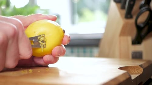 Man zests a bright yellow lemon with grater