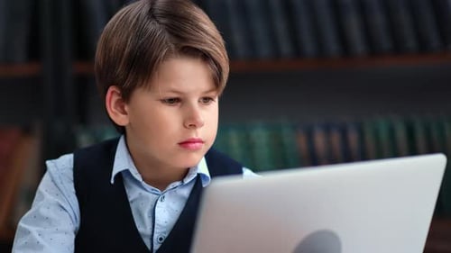Confident Male Kid Pupil Chatting Typing e Learning Use Laptop Library Bookshelves Interior Closeup