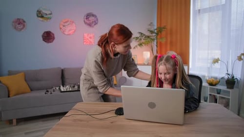 Child Using Laptop as Mother Approaches Indoors