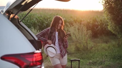 Woman With Car Using Phone in Rural Field
