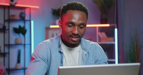 Un mec à la peau noire assis devant un ordinateur et lisant des nouvelles d'amis