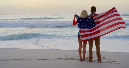 Couple standing with American flag at beach
