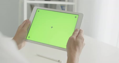 Asian businessman sitting on a chair using tablet with chroma key green screen at office room.