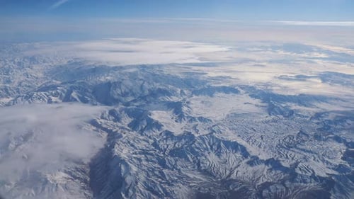 Entfernte Bergkette gegen blauen Himmel aus Flugzeugfenster