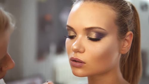 Nahaufnahme des professionellen Visagisten, der mit einem speziellen Pinsel Lippenstift auf eine