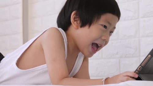 Cute little boy using tablet computer at home.