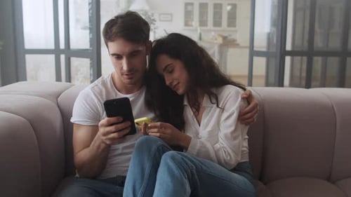 Couple Relaxing Together on Couch Looking at Phones