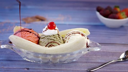Banana Split Sundae with Chocolate Sauce Being Drizzled