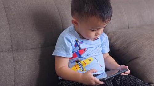 Toddler Boy Plays With Tablet on Couch