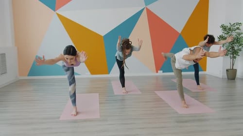 Slow Motion of Youth Exercising in Yoga Studio Doing Balancing Asanas on Mats