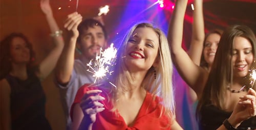 Excited Young Adults Celebrate with Sparklers at Night