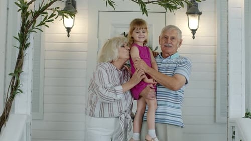 Grandparents Hold Granddaughter on Sunny Porch Together