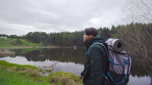 Hiker Walking Beside a Lake on Overcast Day
