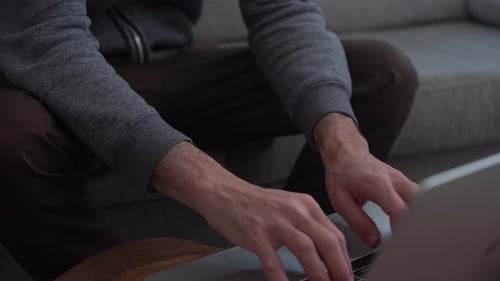 Close-up nas mãos do homem digitando em um laptop em sua casa sentado no sofá