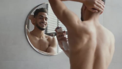 Man Applying Deodorant in Front of Bathroom Mirror
