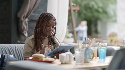 African Girl Browsing the Net on Tablet in Cafe