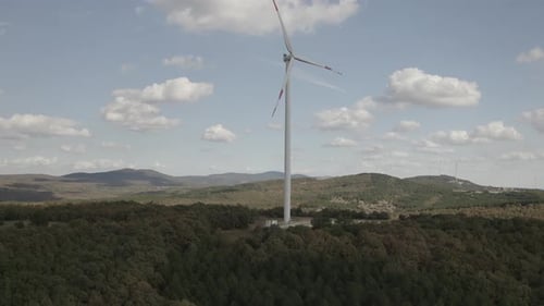 Wind Turbine Spins on Hilltop Under Cloudy Sky