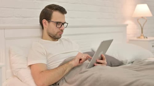 Man in Bed Using Tablet at Night