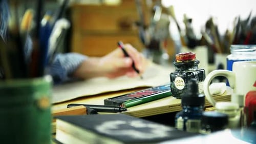 Artist Hand Drawing at Cluttered Desk