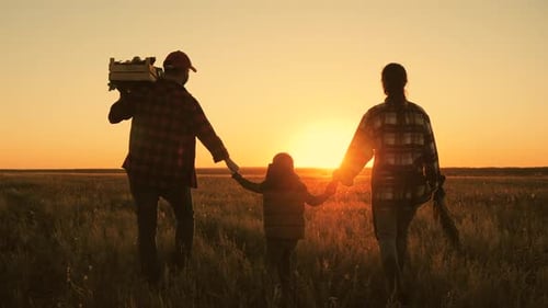 Family Walking Through Field at Golden Sunset