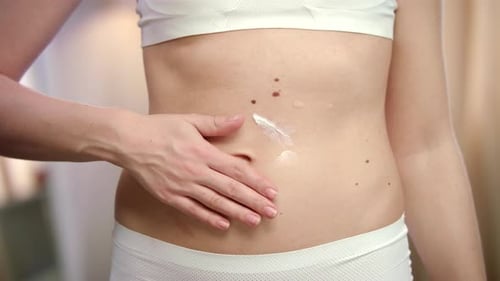 Handauftragende Körpercreme für Frauen auf den Bauch. Hautpflege für Damen
