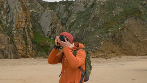 Young Man Takes Picture Against Steep Cliff on Sea Beach
