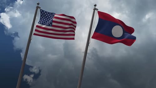 United States and Laos Flags Waving Against Cloudy Sky