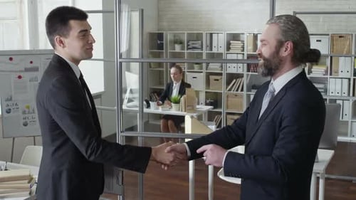Two Men Shake Hands After Deal in Office