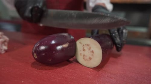 Chef Cutting Fresh Eggplant in Half
