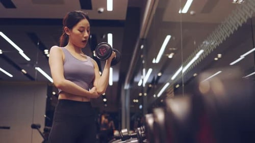 Asian young Female hands taking bodybuilding dumbbells in gym club.